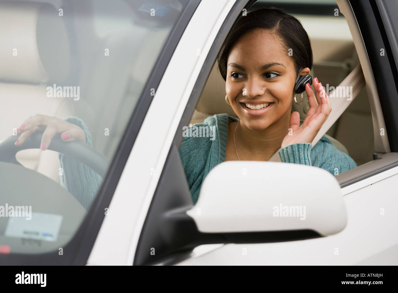 Donna africana utilizzando dispositivo vivavoce in auto Foto Stock