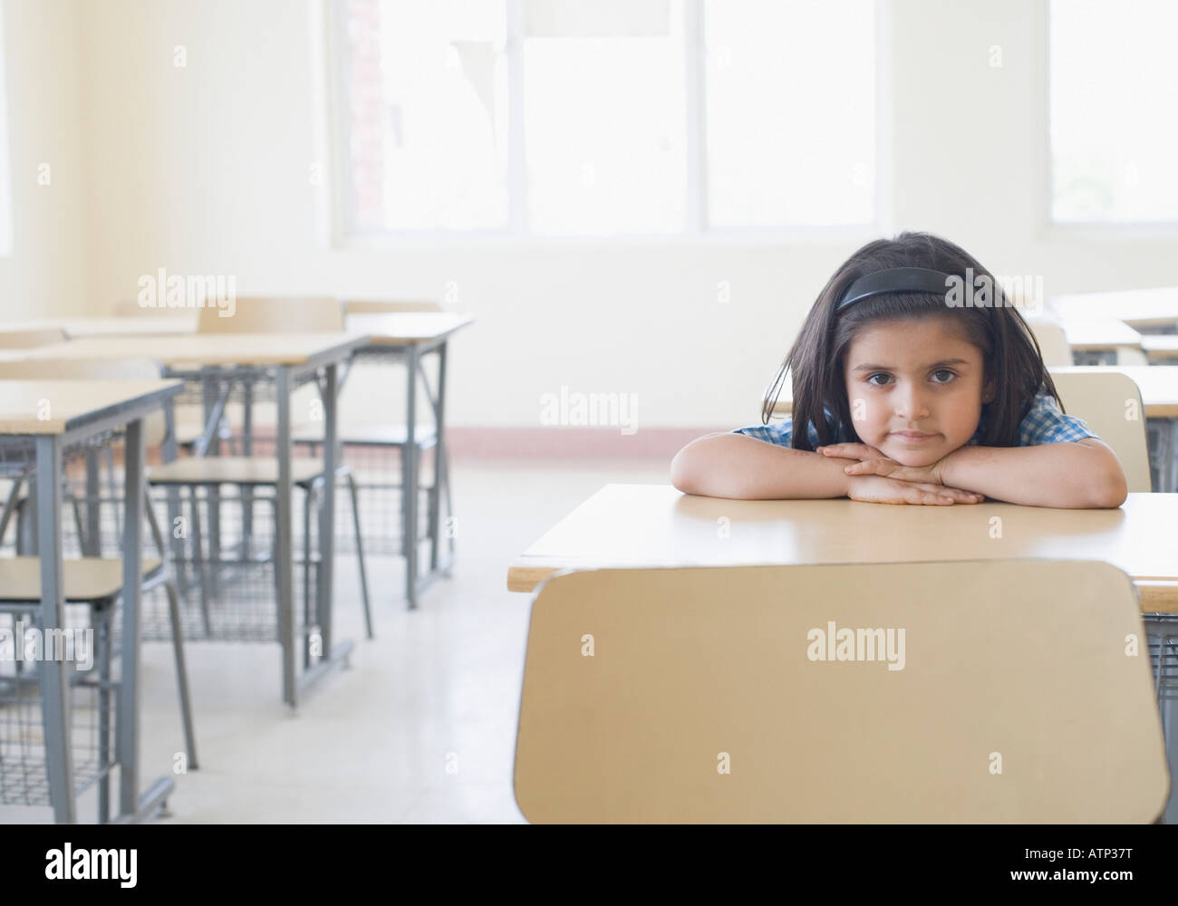 Ritratto di una scolaretta appoggiato su una scrivania in una classe Foto Stock