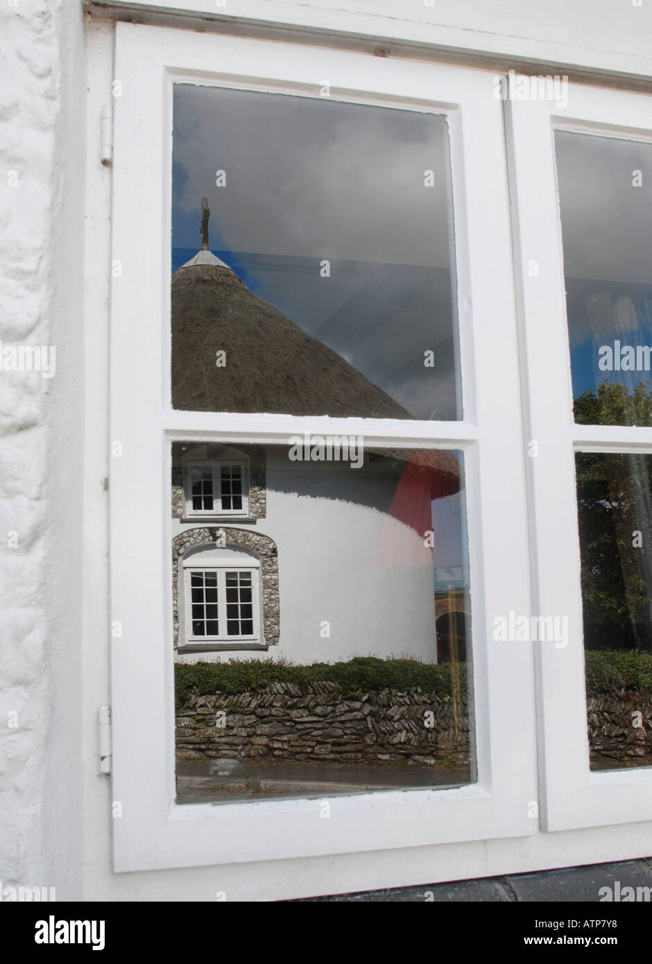Una casa rotonda a Veryan Cornwall Regno Unito riflessa nella finestra di esso s il partner al di là della strada Foto Stock