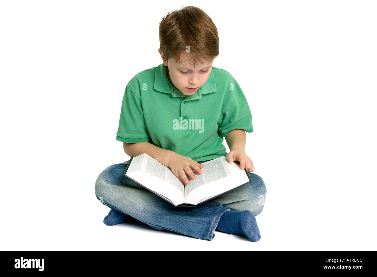 Ragazzo seduto gambe incrociate la lettura di un libro isolato su uno sfondo bianco Foto Stock