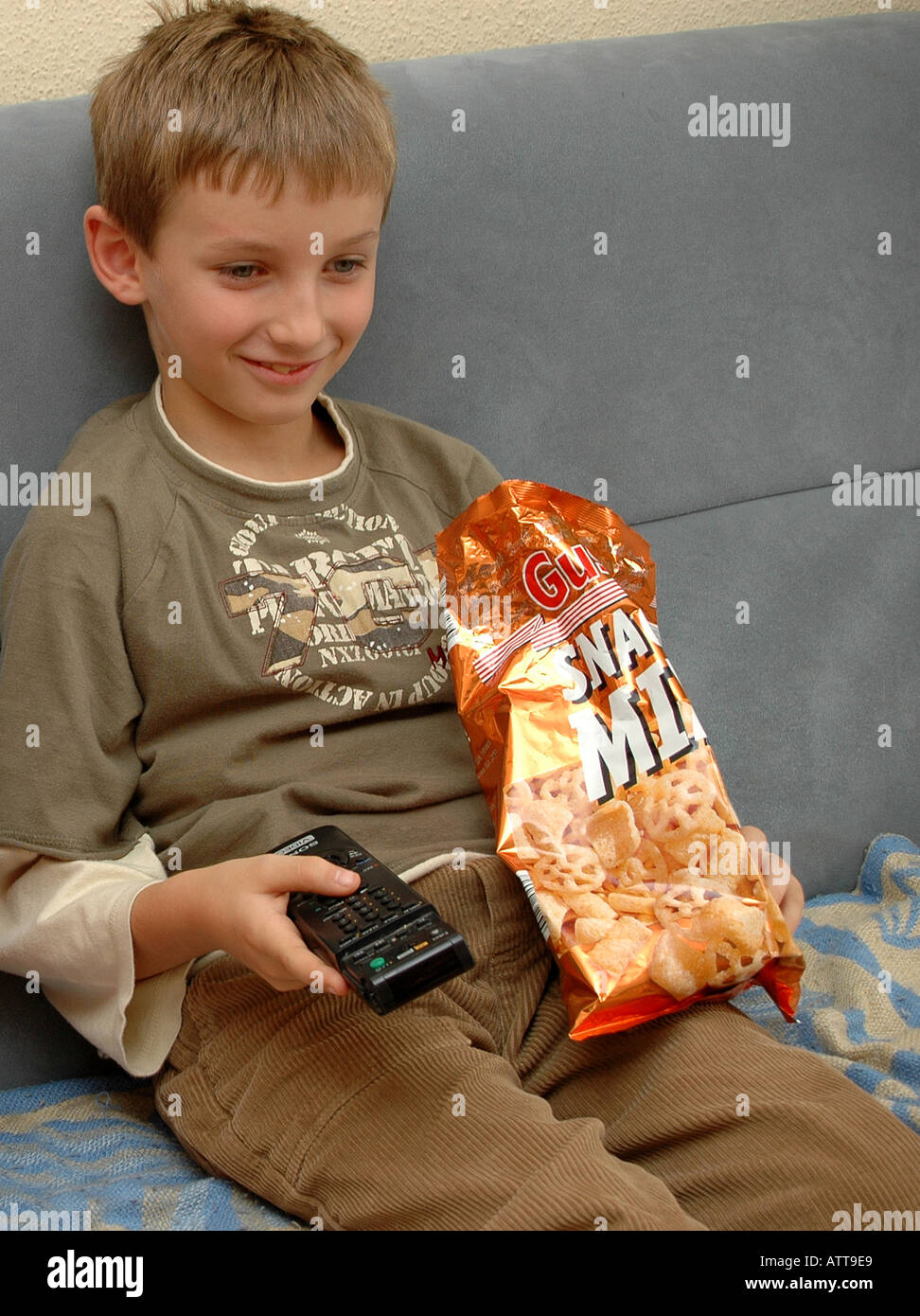 Signor Junge beim Fernsehen mit Fernbedienung und Chips signor ragazzo è di guardare la TV e mangiare patatine Bildagentur Begsteiger online Foto Stock
