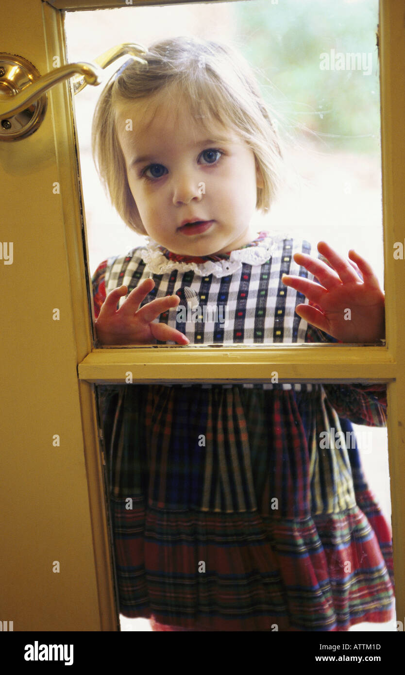 Preschooler femmina guardando attraverso la finestra Foto Stock
