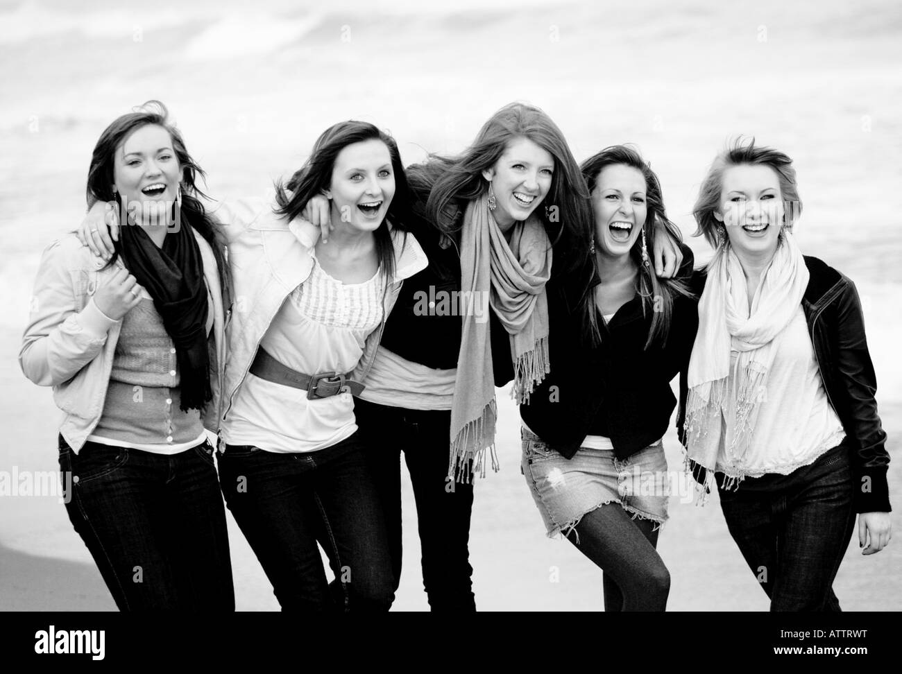 Un gruppo di adolescenti di una ragazza amici su una spiaggia in bianco e nero di ridere e divertirsi Foto Stock