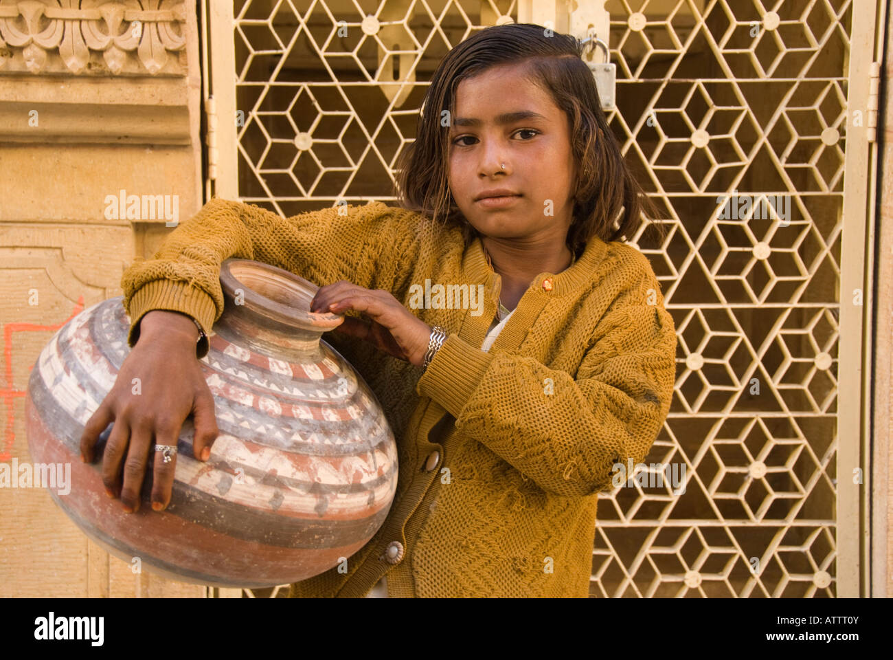 Giovane ragazza che porta una brocca di acqua e in piedi di fronte a un cancello ornati. Foto Stock