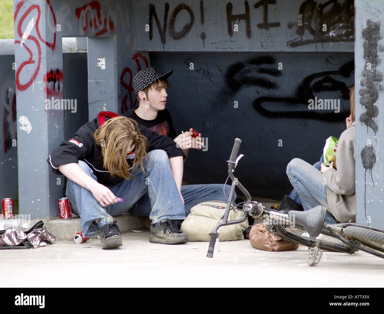 Gli adolescenti seduti sotto un halfpipe in uno skatepark. Foto Stock
