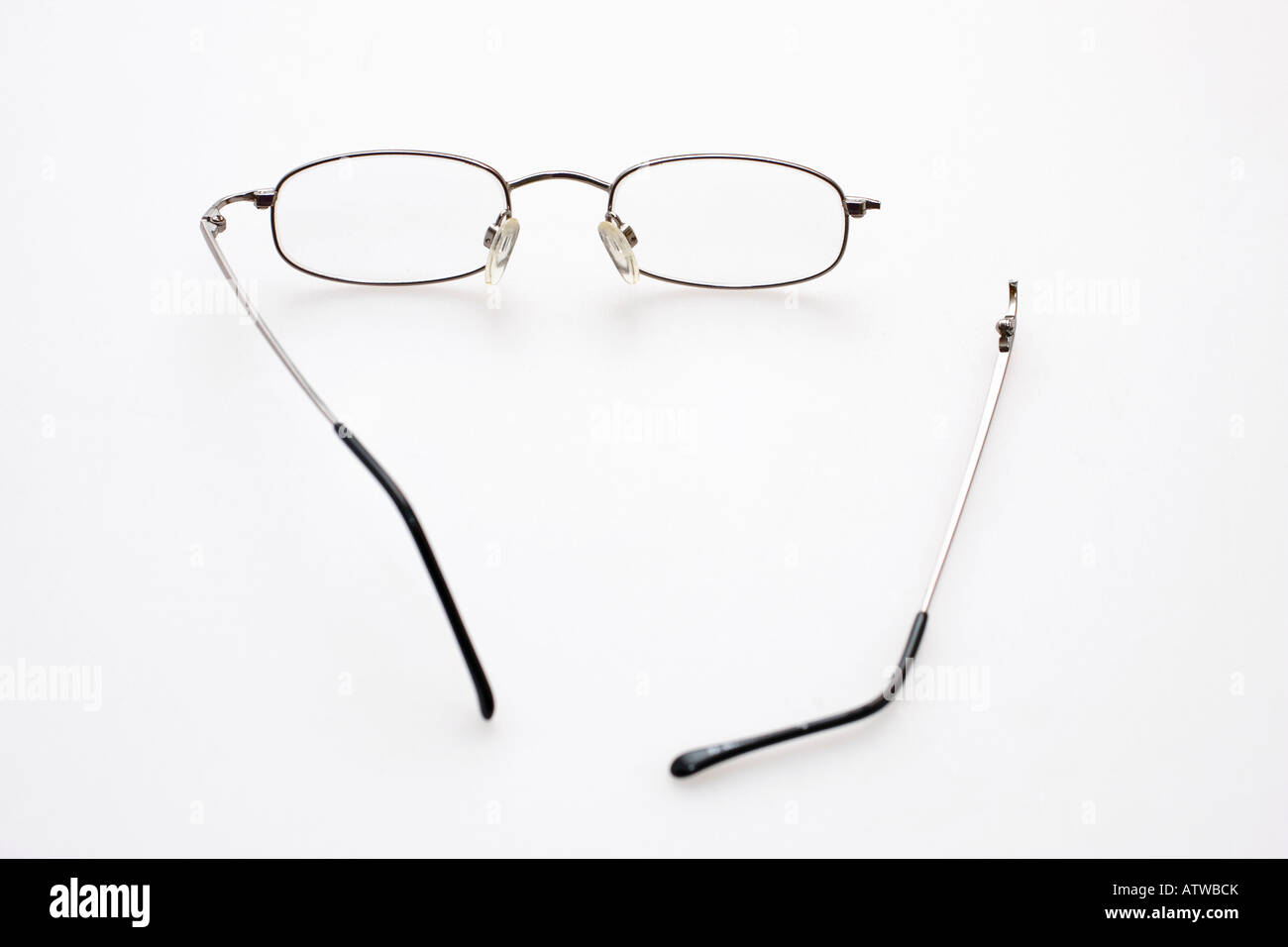 Un paio di occhiali con un braccio rotto su uno sfondo bianco Foto Stock