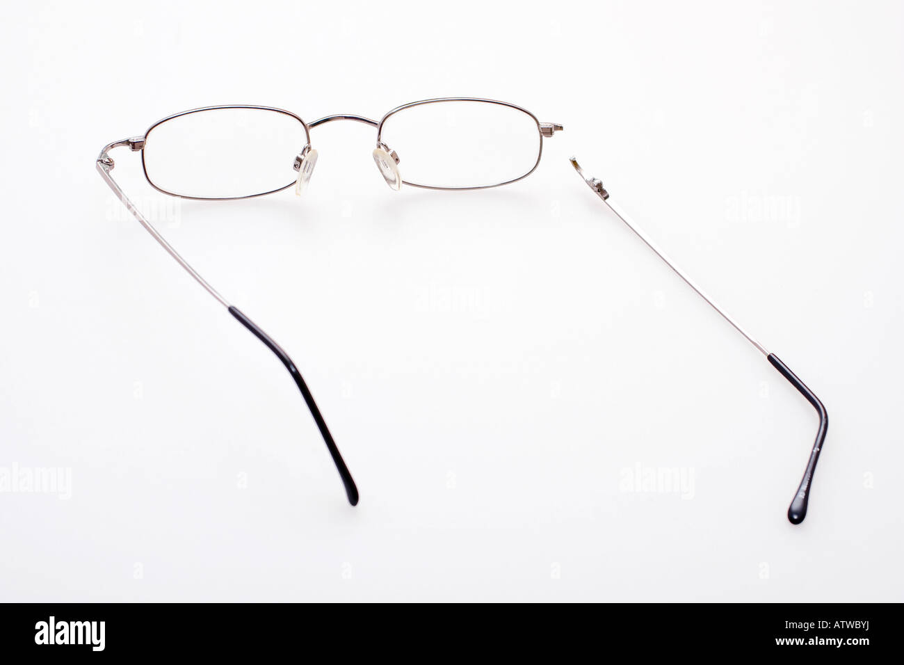 Un paio di occhiali con un braccio rotto su uno sfondo bianco Foto Stock