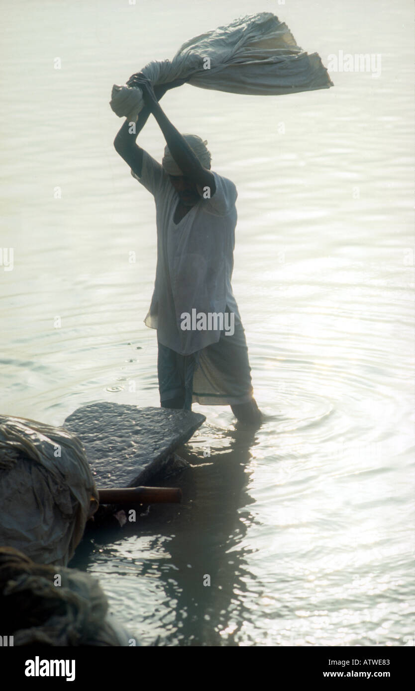 DHOBI WALLAH o lavanderia uomo batte i vestiti bagnati contro le rocce con i tradizionali metodi di lavanderia VARANASI INDIA PH DAN WHITE Foto Stock