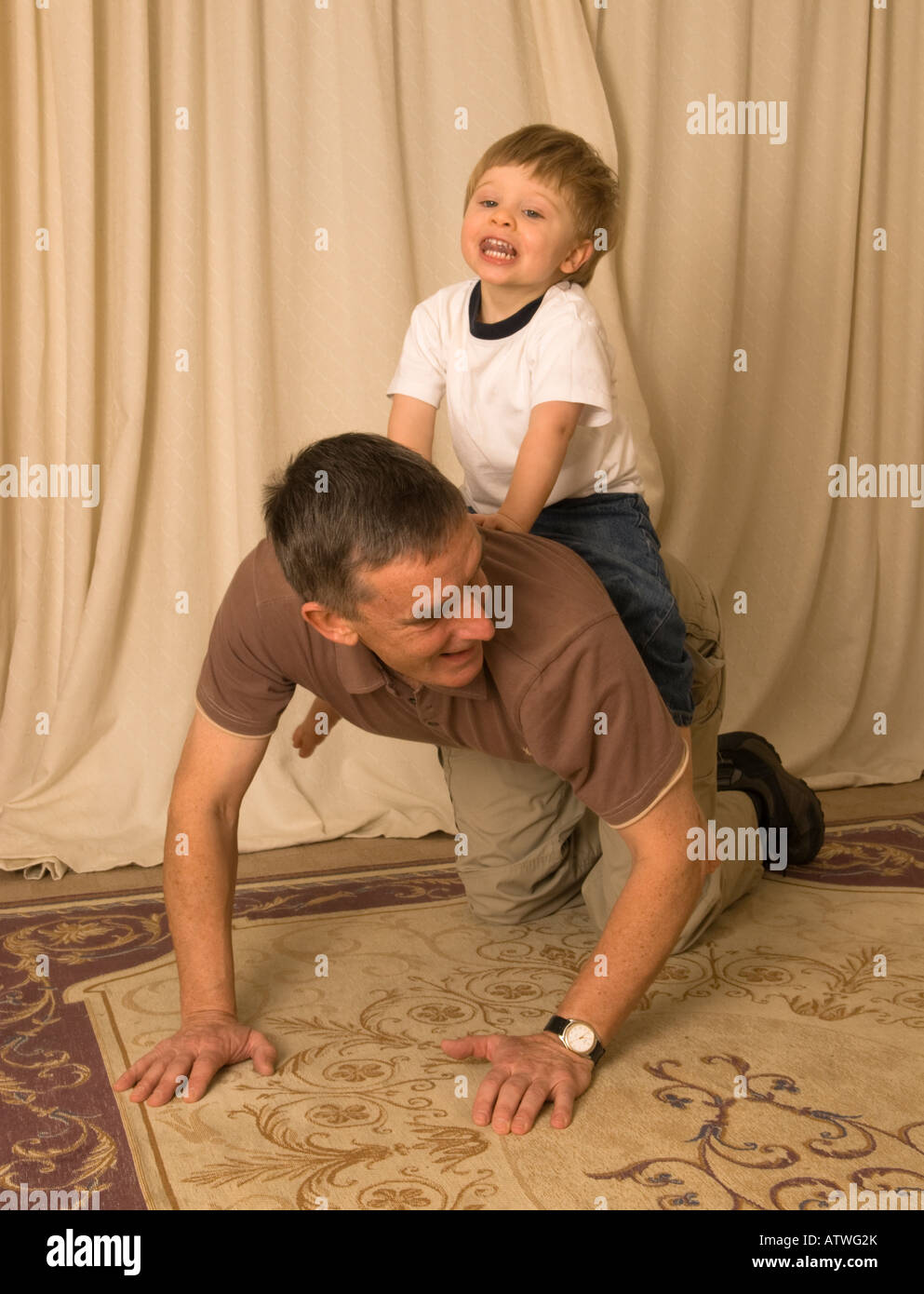 Nonno vecchio padre giocando con il nipote figlio dandogli un piggyback o cavallo Foto Stock