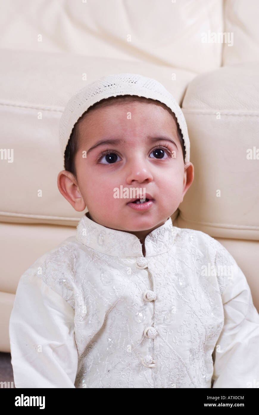 Arabo 1 anno vecchio ragazzo indossando il tradizionale abito islamico cercando Foto Stock