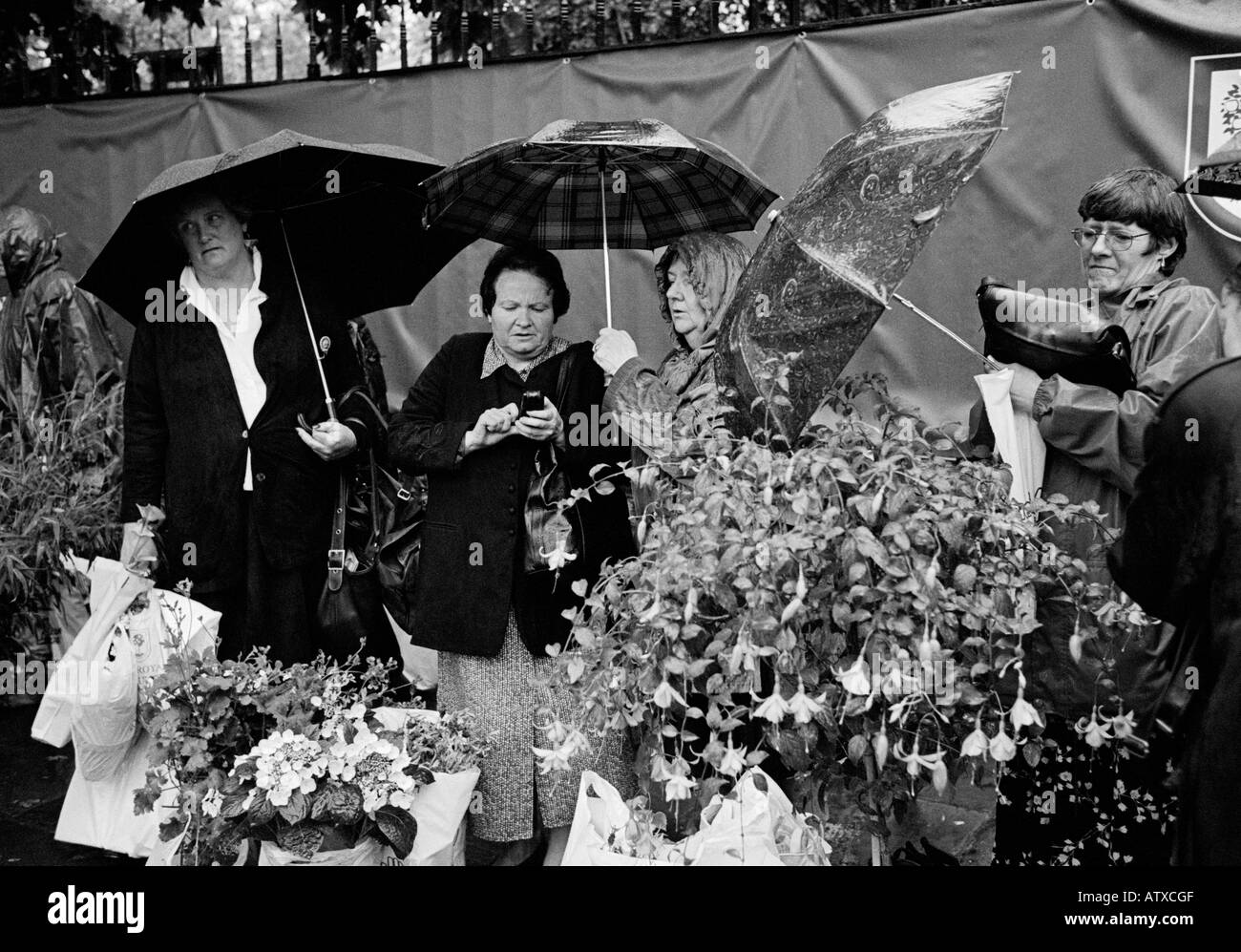 I visitatori di lasciare il Chelsea Flower Show sotto la pioggia Foto Stock