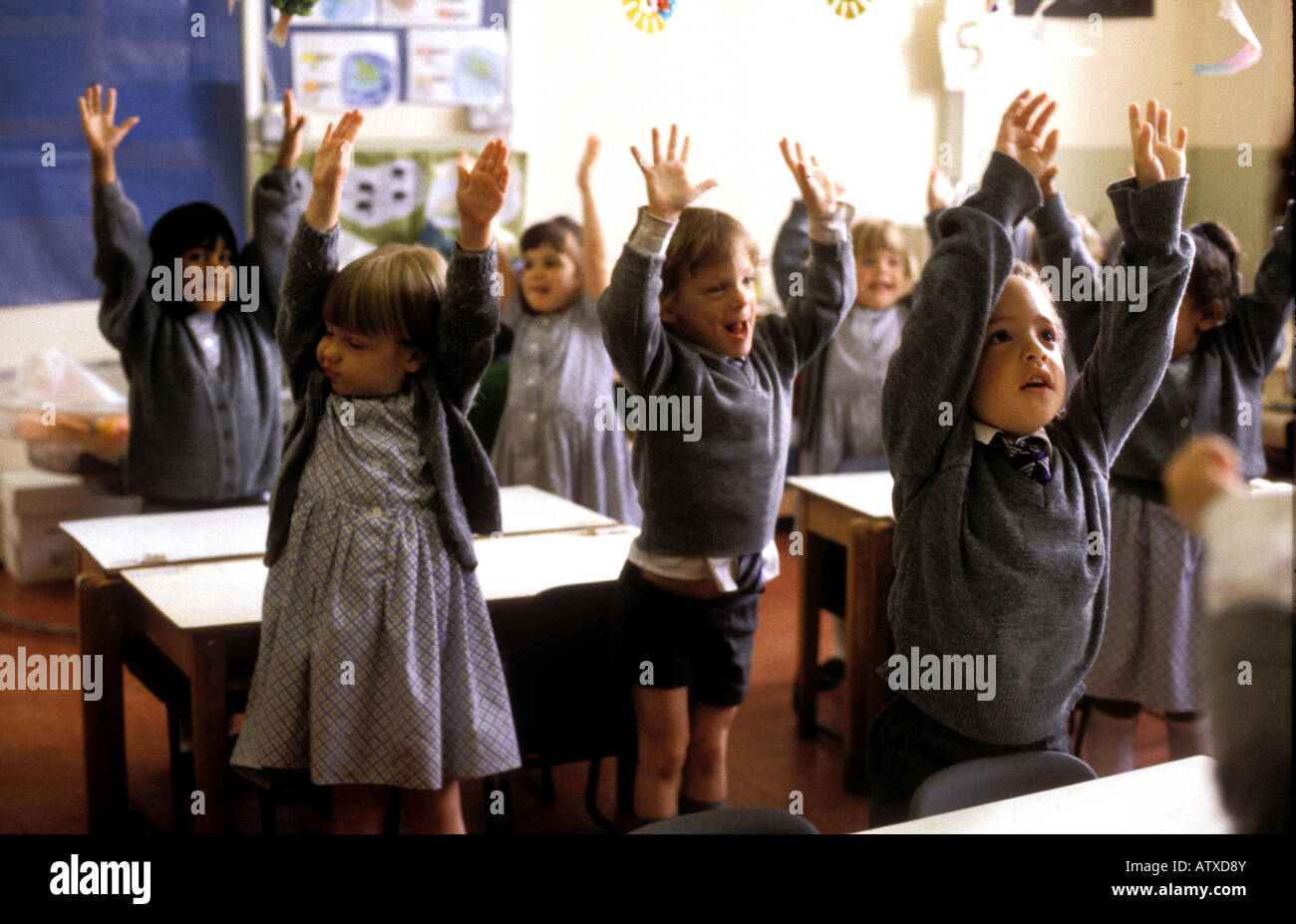 Vivaio età i bambini nel sud di Londra scuola preparatoria in piedi con le braccia stretching alta Foto Stock