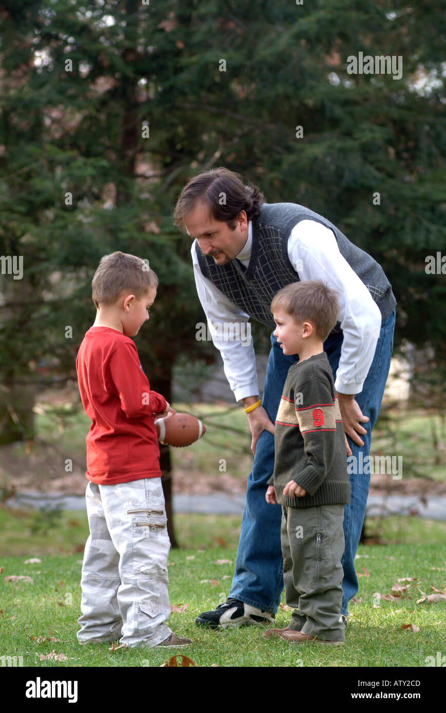 Elementi maschio di una famiglia estesa di giocare a calcio nel loro cortile anteriore sul giorno del Ringraziamento Foto Stock