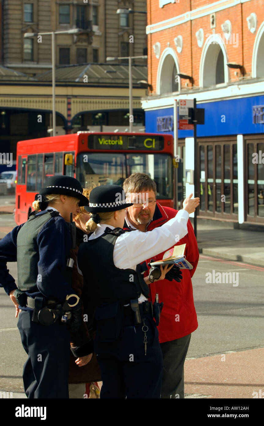 Poliziotta officer sottolineando la direzione ai turisti Victoria Street SW1 London Regno Unito Europa Foto Stock