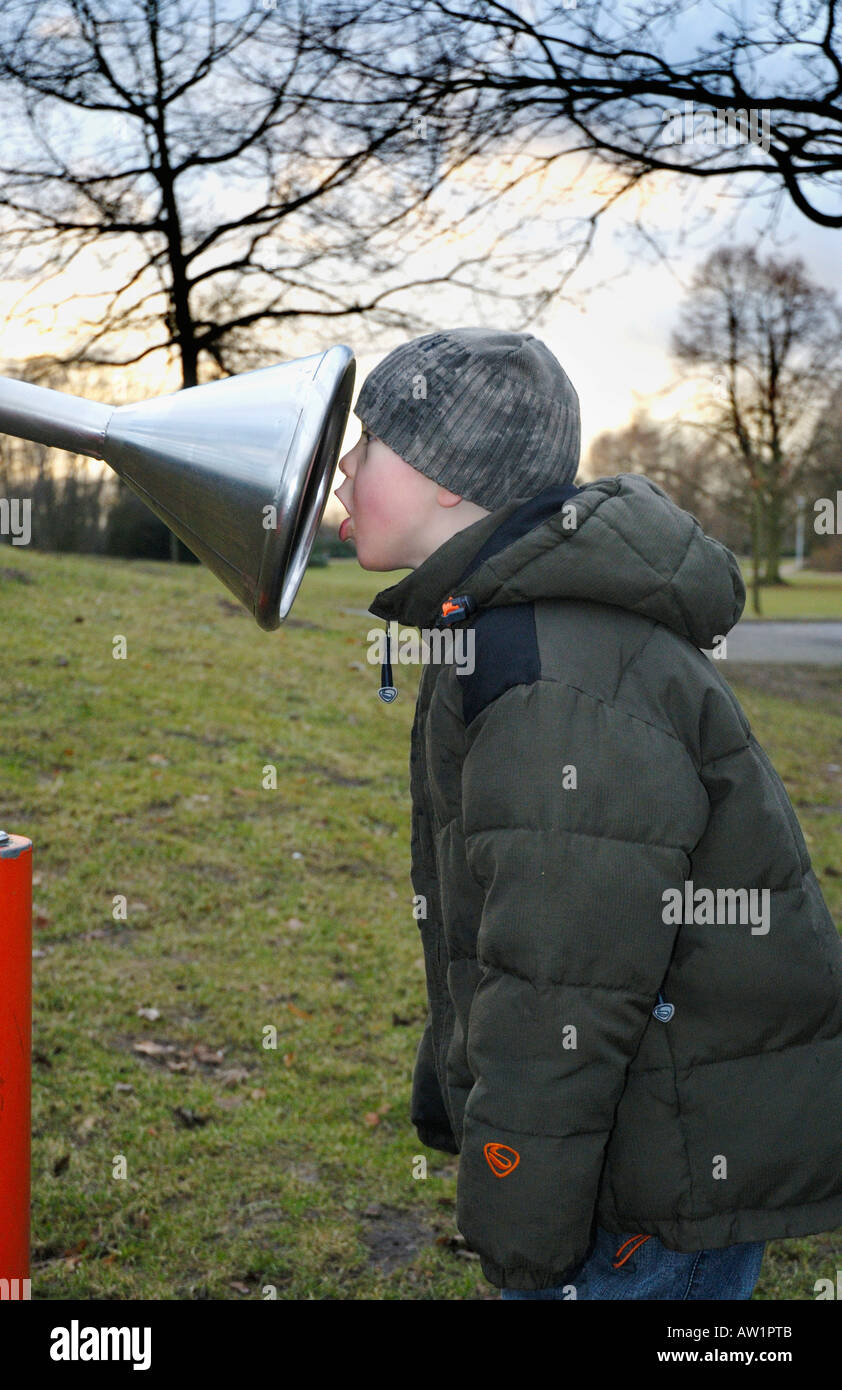 Little Boy bloccata la sua testa in un imbuto di un citofono in un parco giochi Foto Stock