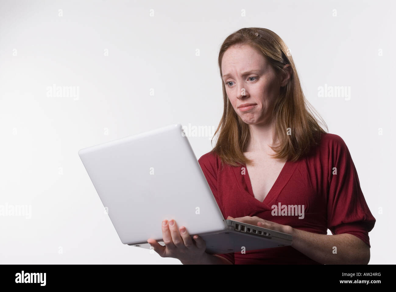 Una giovane donna guarda giù al suo computer portatile con uno schermo sconcertato sguardo sul suo viso Foto Stock