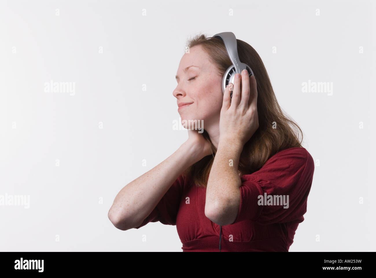 Una giovane donna con gioia ascolta musica in cuffia mentre le sue mani tenere gli auricolari Foto Stock