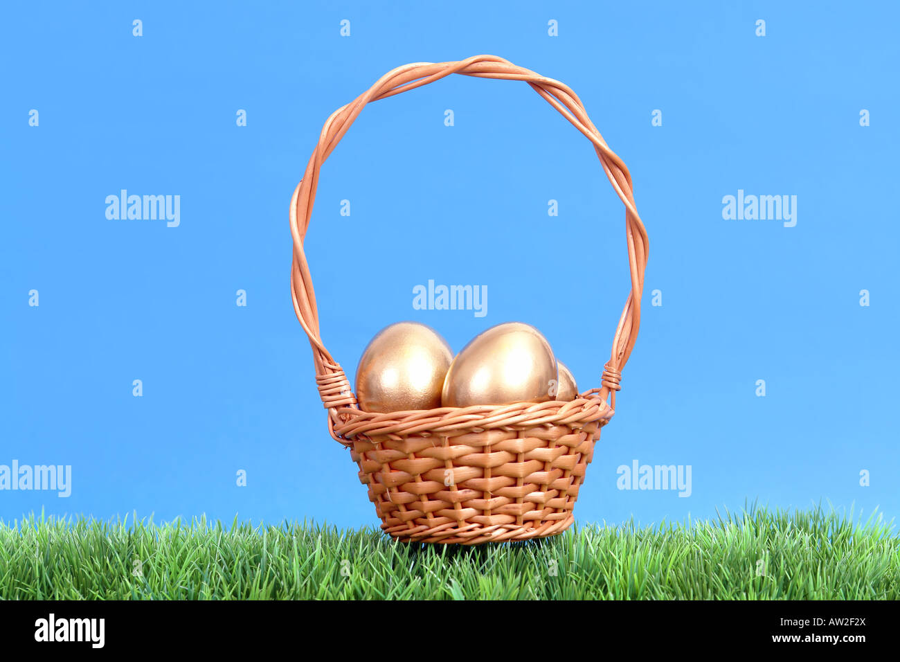 Golden uova nel cesto in vimini di erba oltre il cielo blu Foto Stock