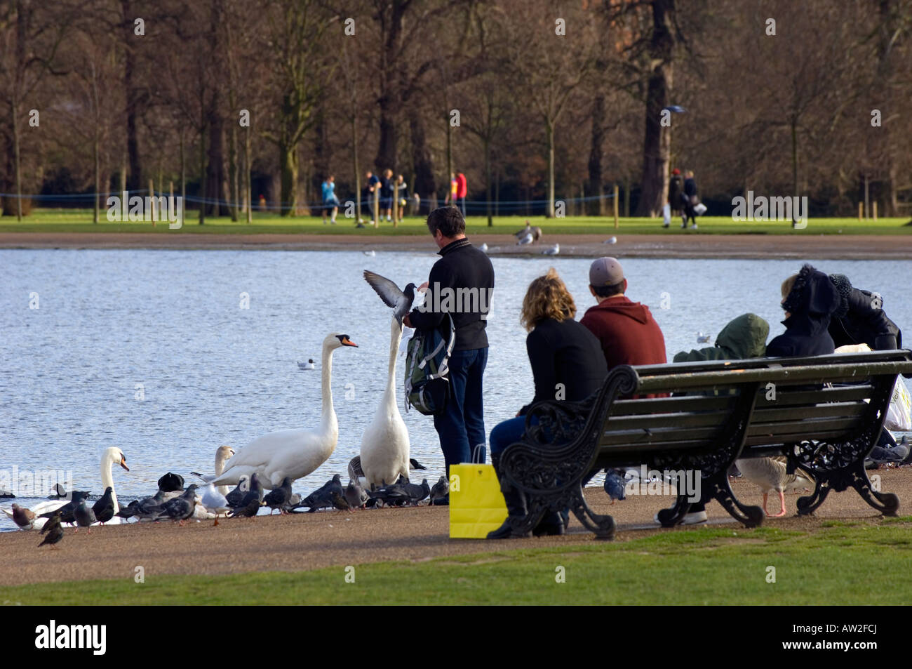 Persone che passeggiano e alimentazione di uccelli dal Round Pond Kensington Gardens W8 London Regno Unito Europa Foto Stock