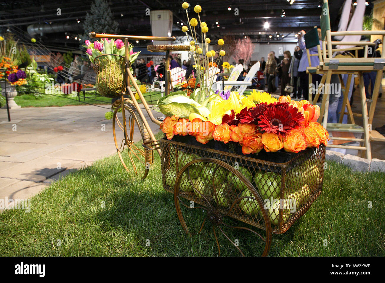 Vecchia bicicletta con grande rimorchio quadrato sul retro base riempita con mele verdi e sormontato da un fiore display Foto Stock