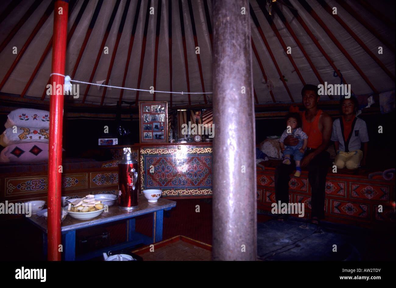 La famiglia in posa sul loro letto con tipiche decorazioni mongola all'interno di una tenda ger, vicino al lago di Terkhiin Tsaagan Nuur, Arkhangai, M Foto Stock