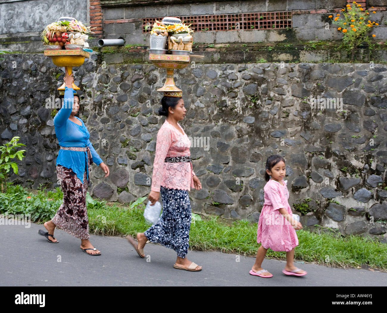 Locale donna Balinese che effettuano il trasporto di merci su vi capi Ubud Bali Indonesia Foto Stock