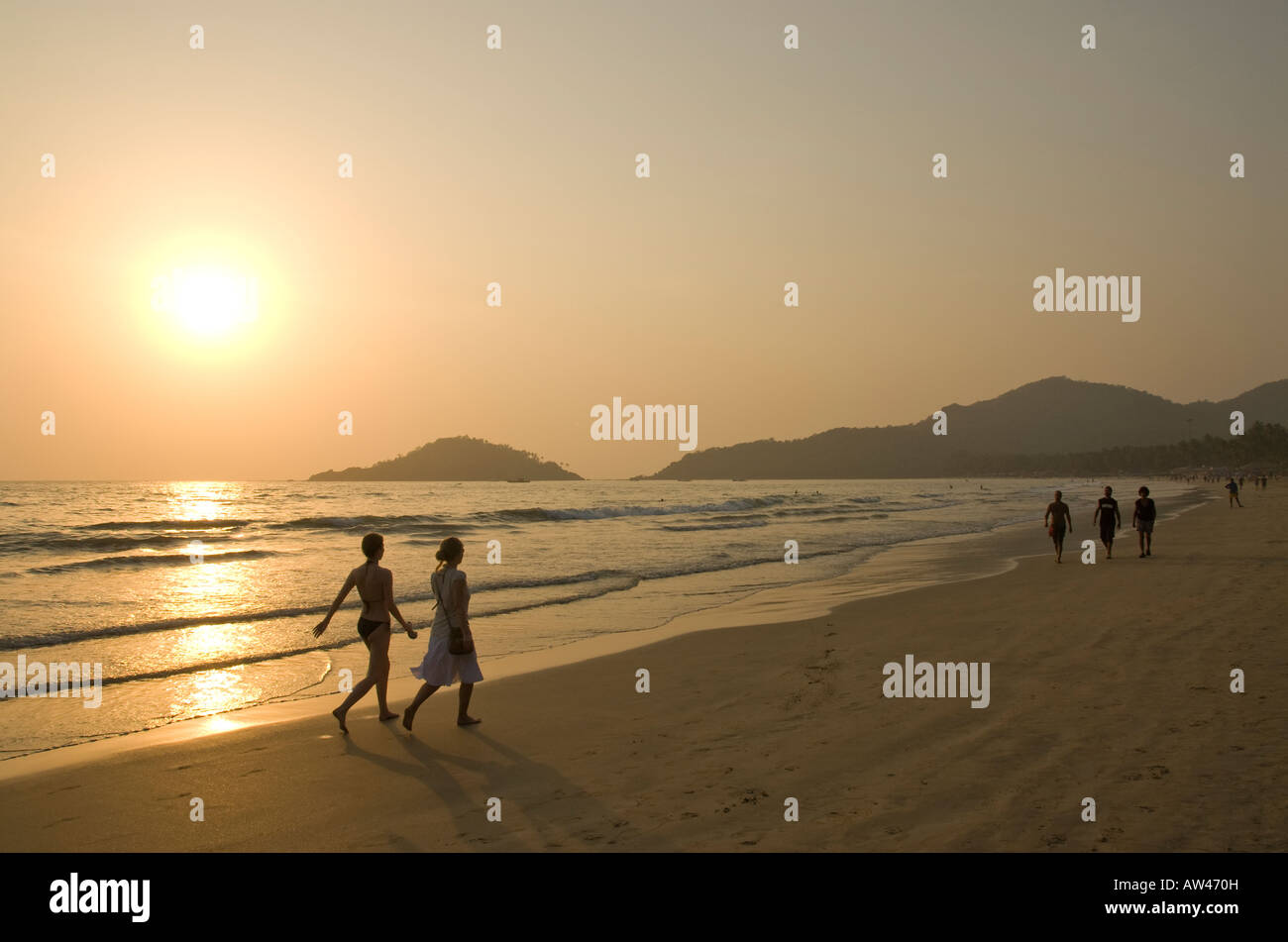 La gente camminare lungo la spiaggia di Palolem in Goa in India del Sud al tramonto Foto Stock