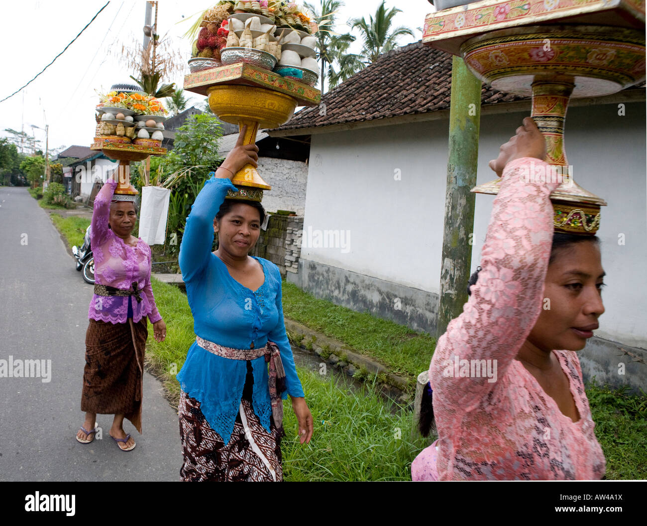 Locale donna Balinese che effettuano il trasporto di merci su vi capi Ubud Bali Indonesia Foto Stock
