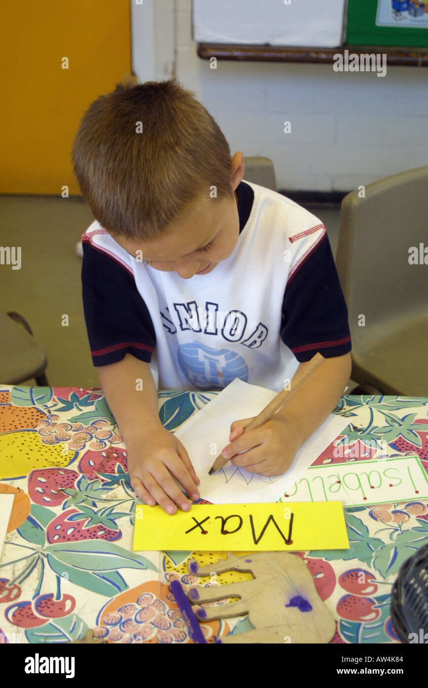 Ragazzo in classe di vivaio per apprendere come scrivere il suo nome Foto Stock