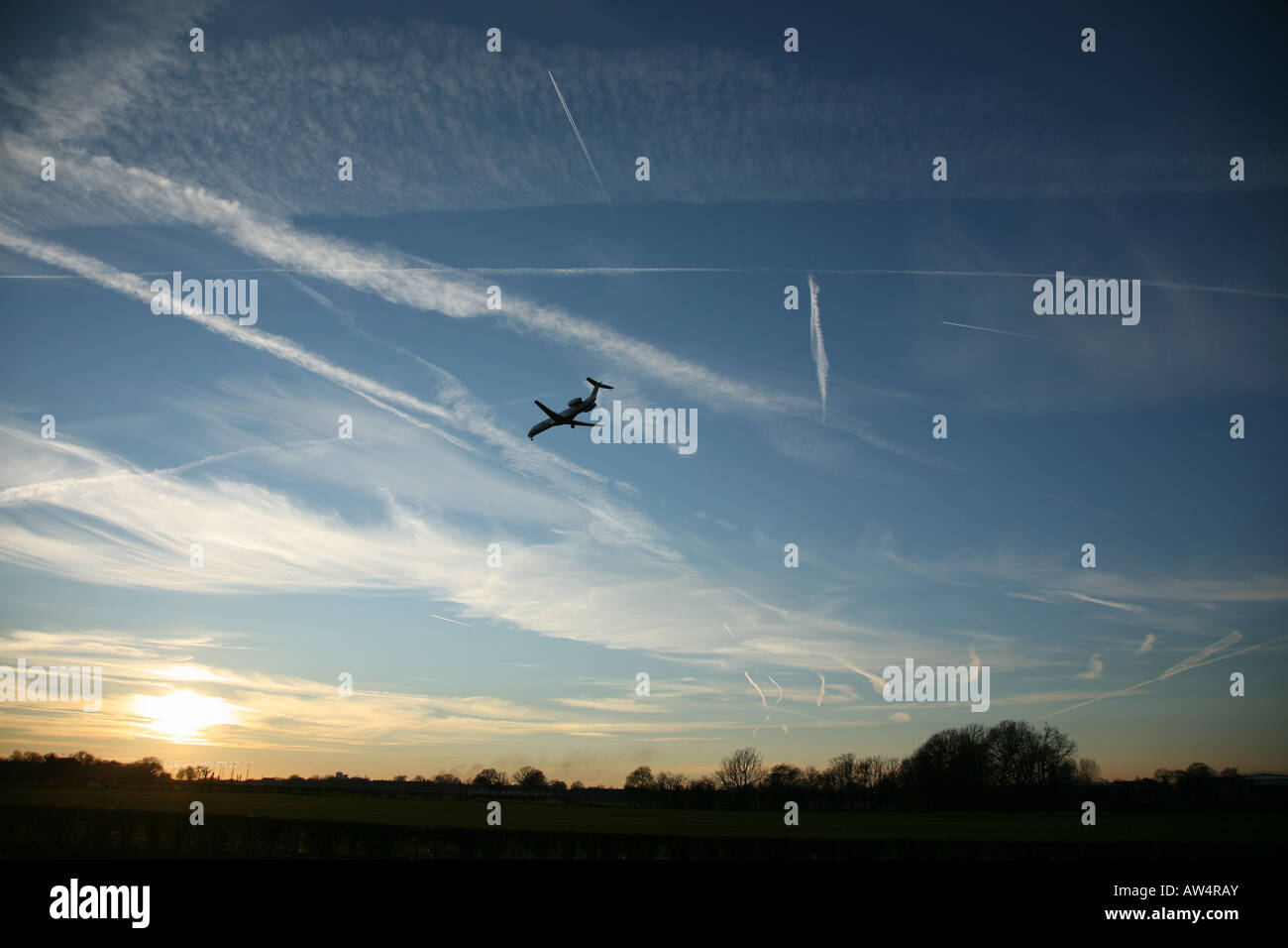 Contrails al tramonto con twin jet aereo sull approccio finale all'Aeroporto di Manchester, Regno Unito Foto Stock