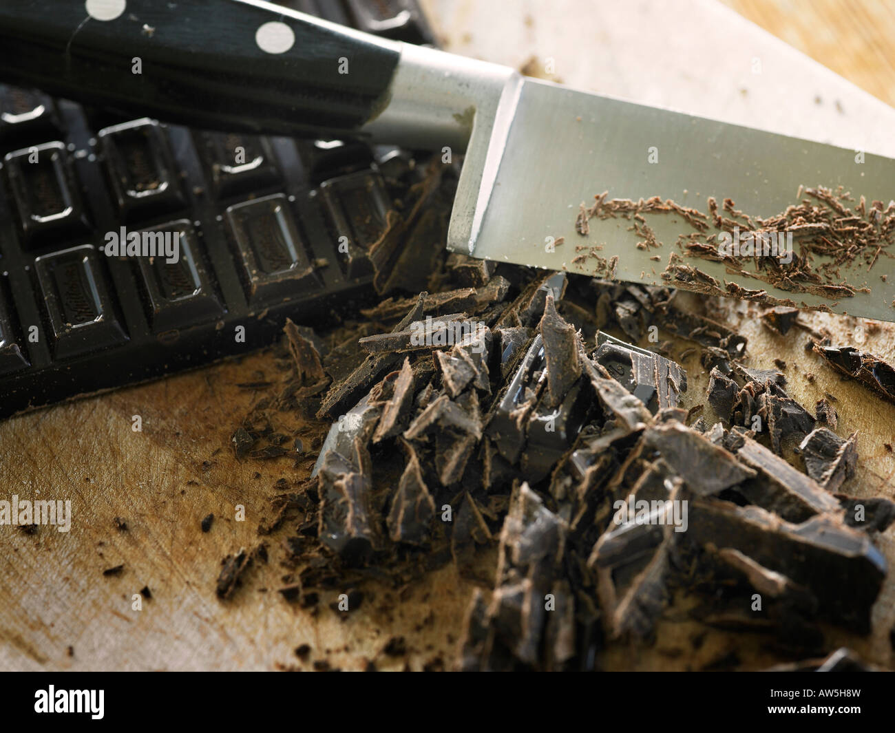 Un blocco di cioccolato tritato su una tavola di legno Foto Stock