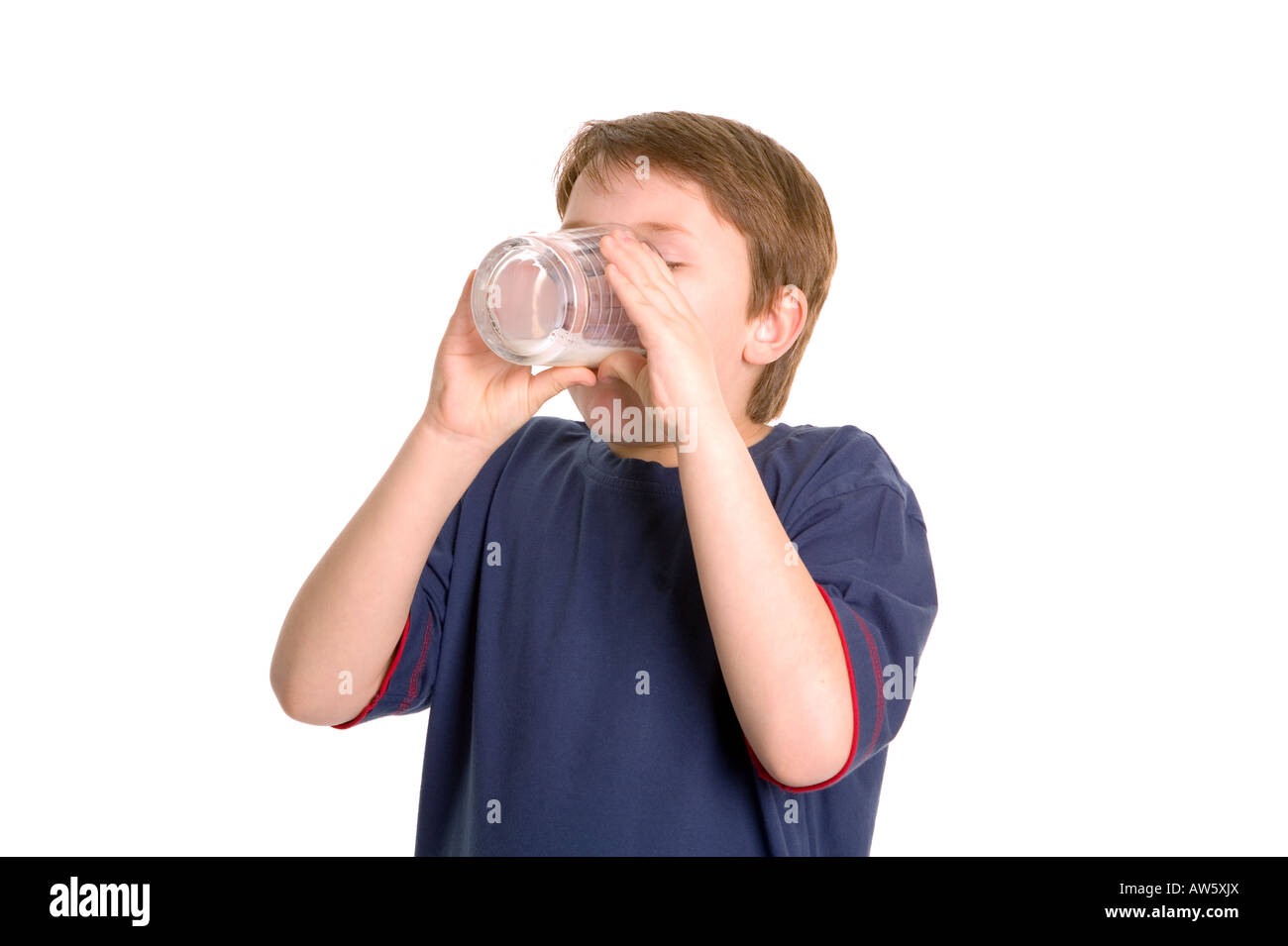 Un giovane ragazzo di bere un fresco bicchiere freddo del latte contro uno sfondo bianco Foto Stock