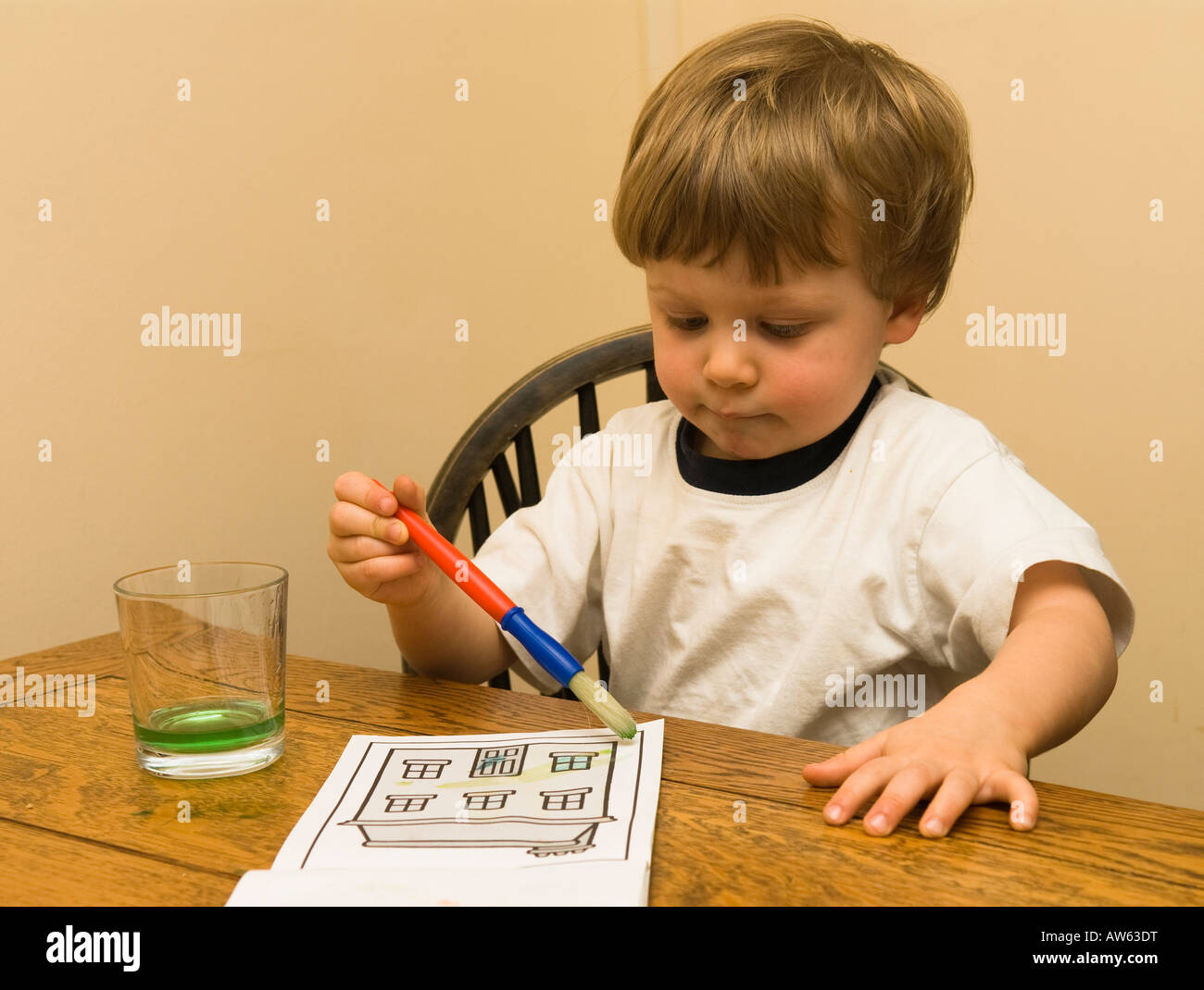 un bambino di due anni che dipinge un quadro al tavolo Foto Stock