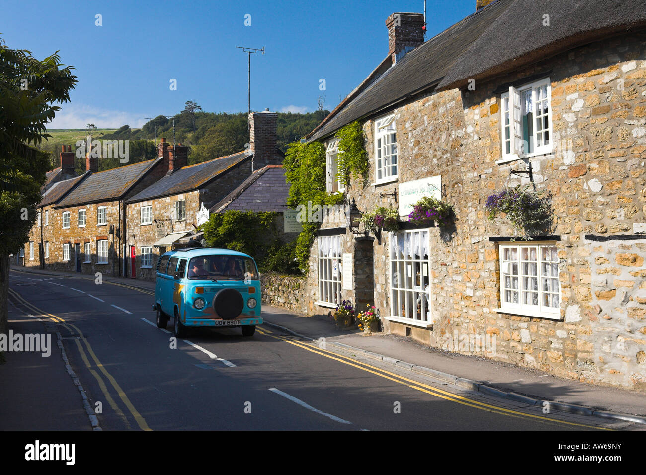 VW Camper passando attraverso il villaggio di Dorset di Abbotsbury Foto Stock