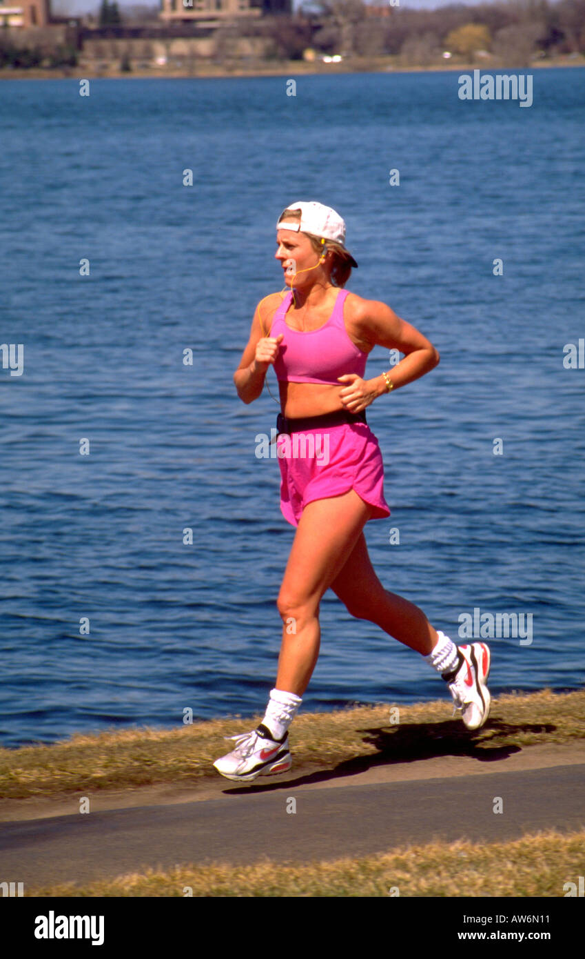 Donna adulta età 26 jogging ascoltando musica attorno al lago Calhoun. Minneapolis Minnesota USA Foto Stock
