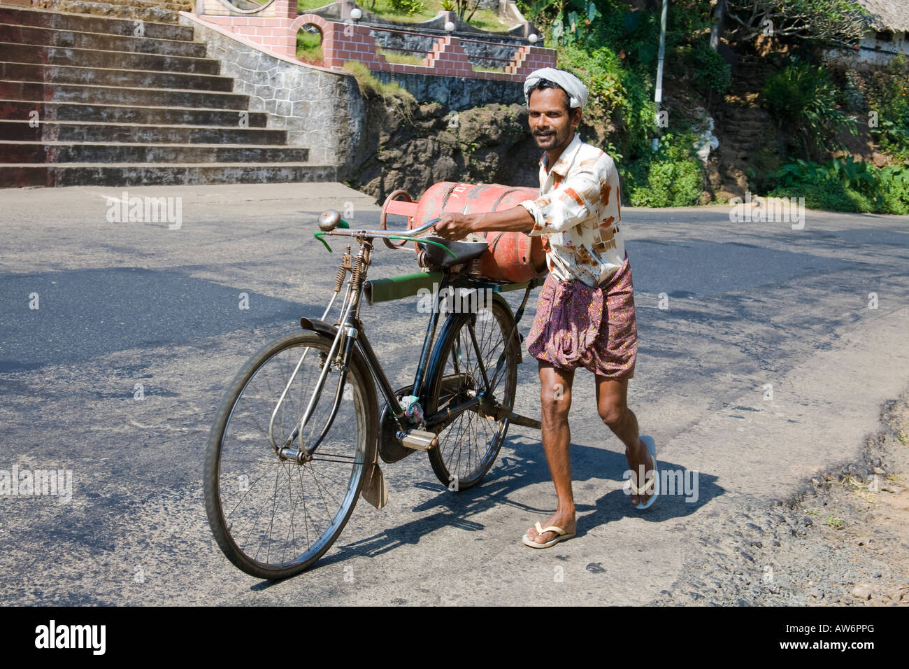 Uomo di spinta, la bicicletta e la bombola del gas in salita, Meenkunnam, Kerala, India Foto Stock