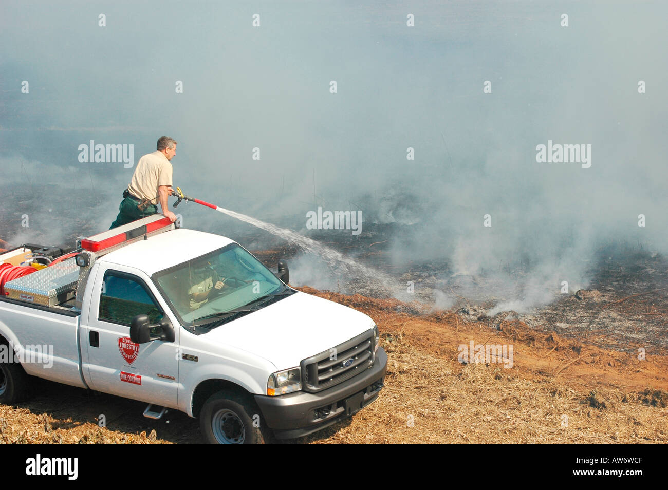 Vigili del fuoco che combattono un incendio a pennello nella zona di Atlanta con acqua e attrezzature di sicurezza Foto Stock