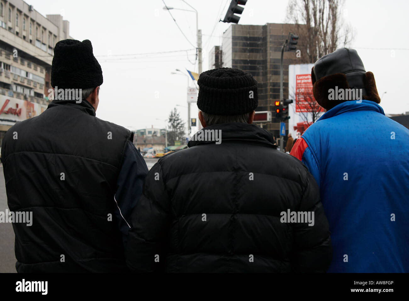Scena urbana con 3 vecchi contadini uomini che indossano diversi black hat forme come si vede dal retro Craiova Romania Foto Stock