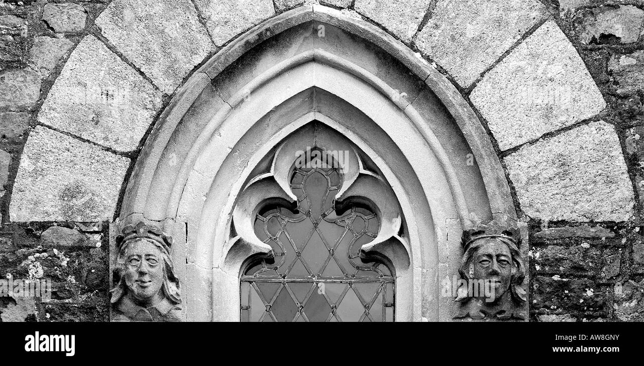 Dettagli architettonici close up di una ad arco gotico la finestra della chiesa con facce di pietra di ciascun lato e chiaro vetro piombato in panoramica Foto Stock