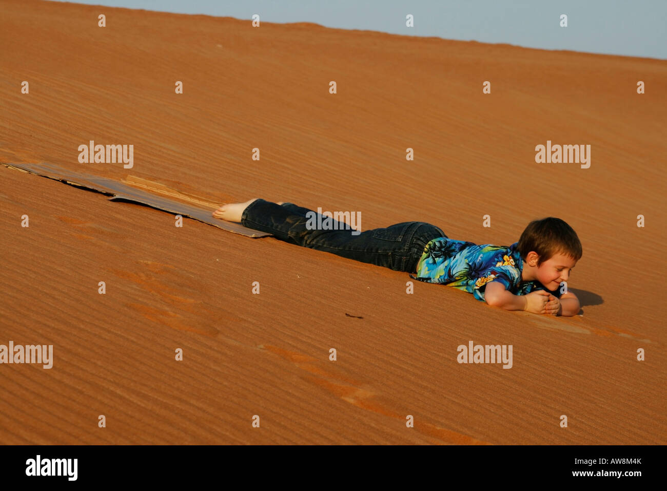 Piccolo bambino giacente nel deserto di sabbia Foto Stock
