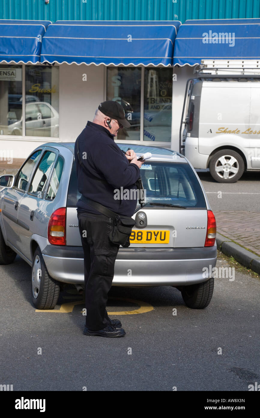 Gwynedd North Wales UK Auto Attendant iscritto i biglietti per il parcheggio per auto parcheggiata in un parcheggio disabili bay Foto Stock
