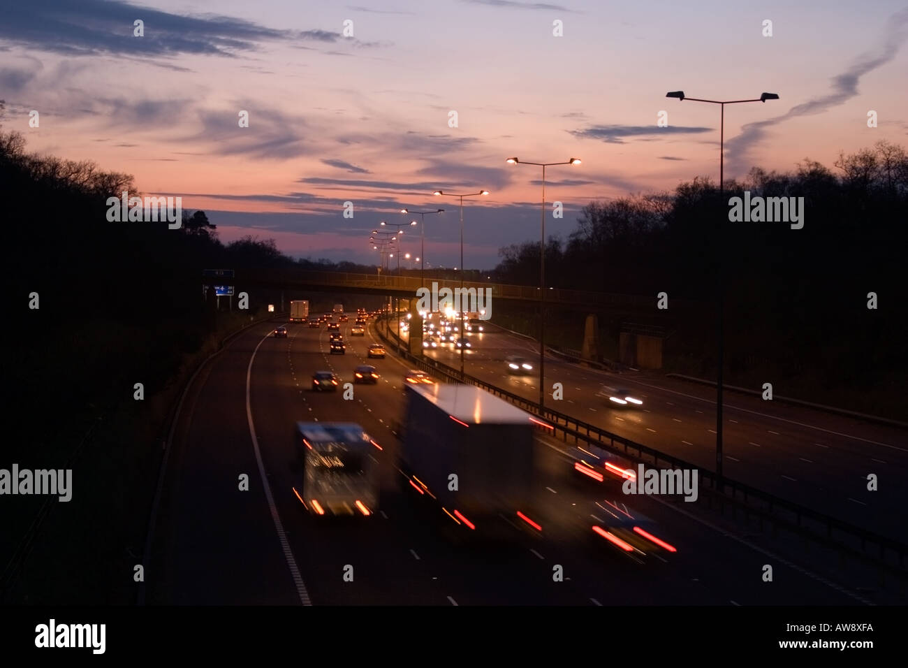 Vista al tramonto del M25 Autostrada nel Surrey in Inghilterra, con traffico sfocata e illuminazione stradale guardando ad ovest Foto Stock