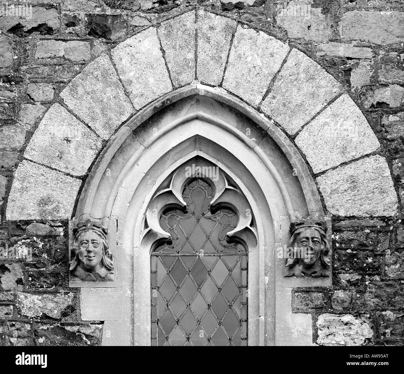 Dettagli architettonici close up di una ad arco gotico la finestra della chiesa con facce di pietra di ciascun lato e chiaro vetro piombato in monocromia Foto Stock