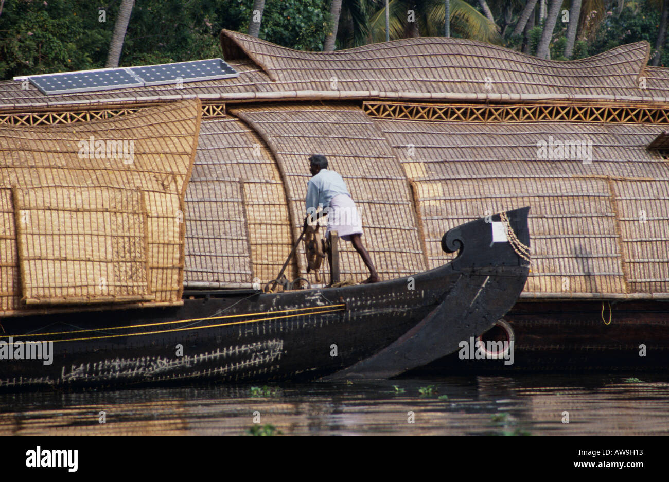 Boat uomo lo sterzo di una casa galleggiante sul backwaters del Kerala, nell India meridionale Foto Stock