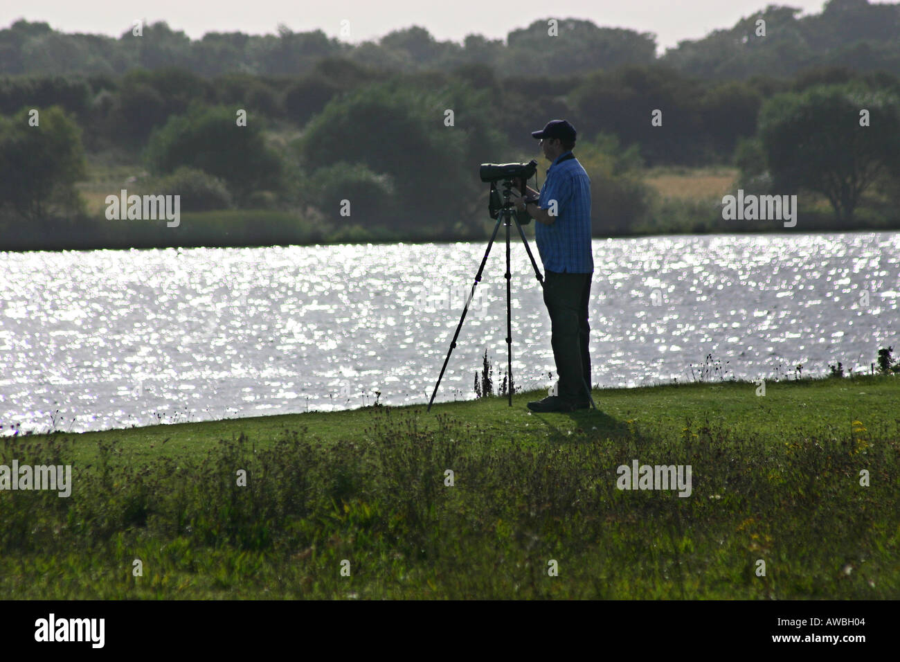 Singolo bird watcher o twitcher in silhouette vicino a un lago nello Yorkshire. Foto Stock
