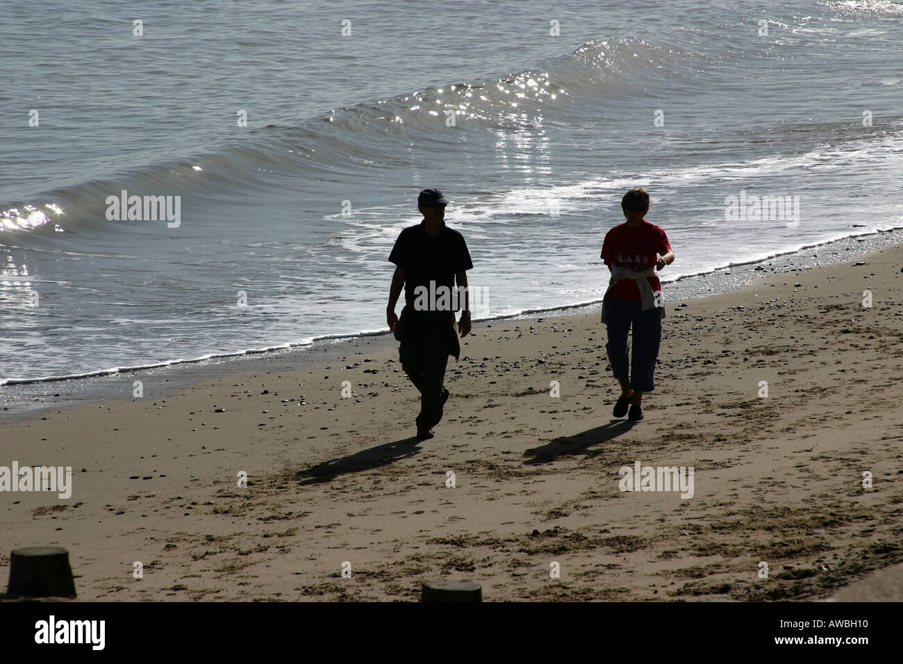 Paio di camminare su una spiaggia in silhouette con forti ombre. Foto Stock