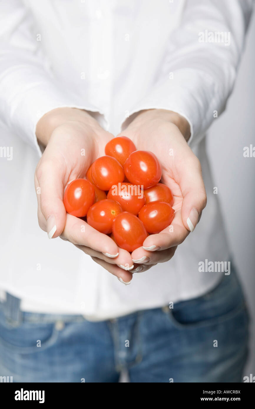 Donna che mantiene molti pomodori in entrambe le mani Foto Stock
