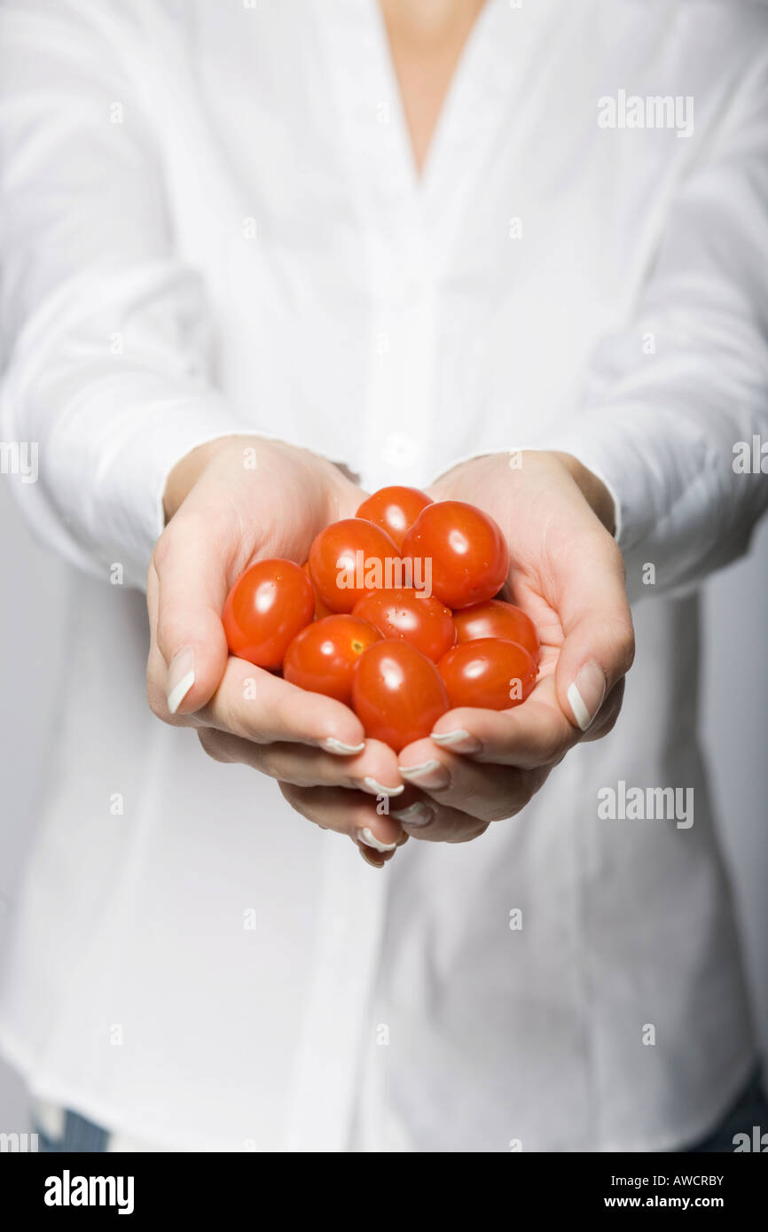 Donna che mantiene molti pomodori in entrambe le mani Foto Stock