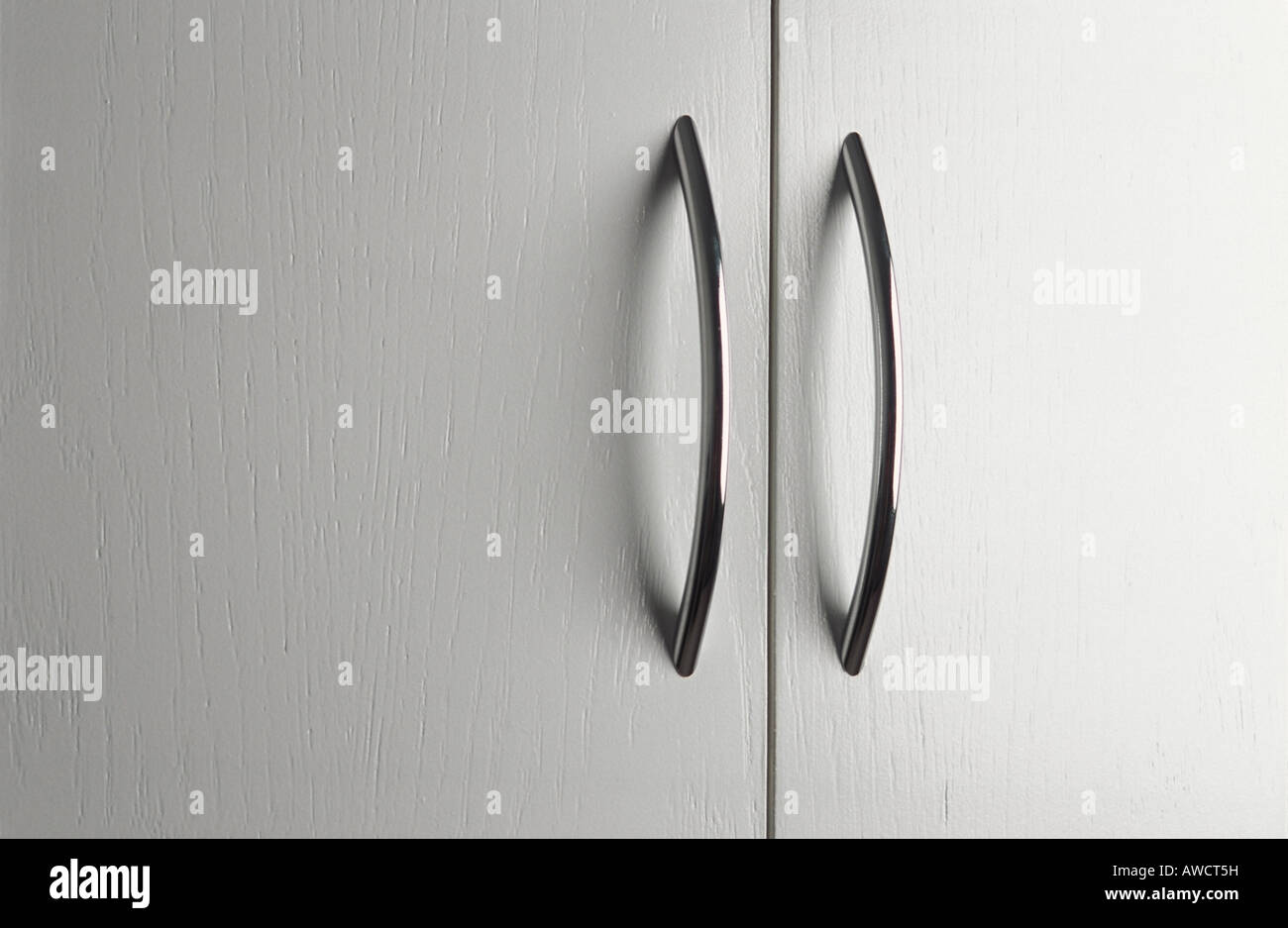 Coppia di maniglie delle porte cromate su bianco antine Foto Stock