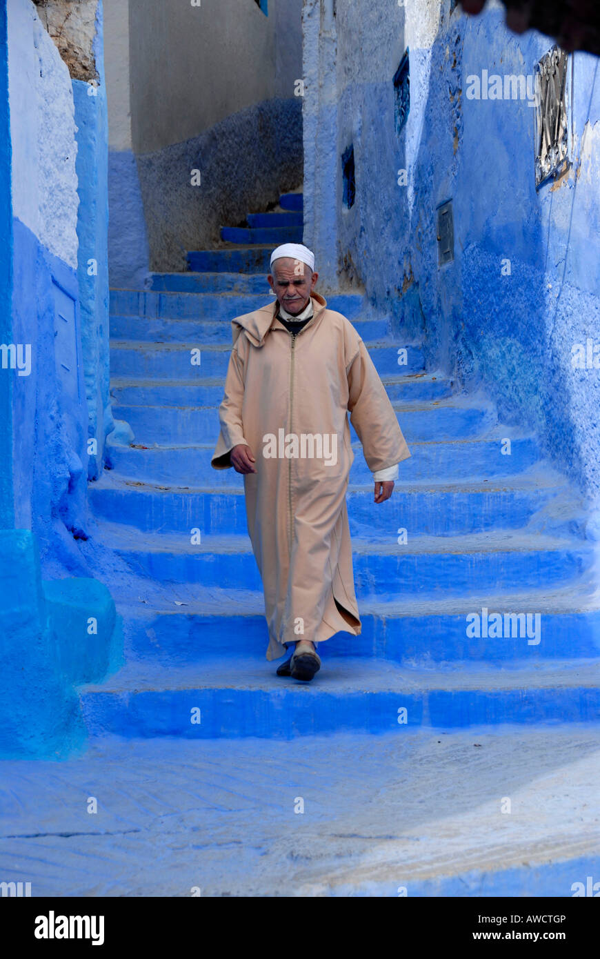 Uomo locale scende le scale in blu luminoso medina Chefchaouen Marocco Foto Stock